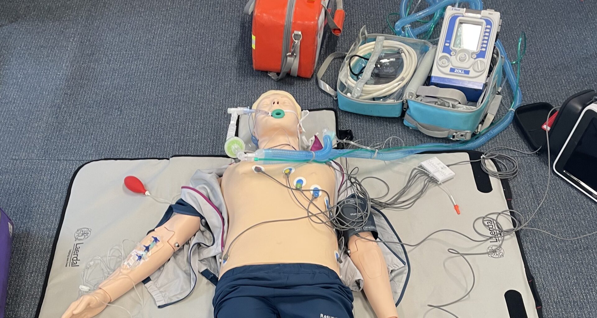 A human sized training manikin with wires connected to it's chest.