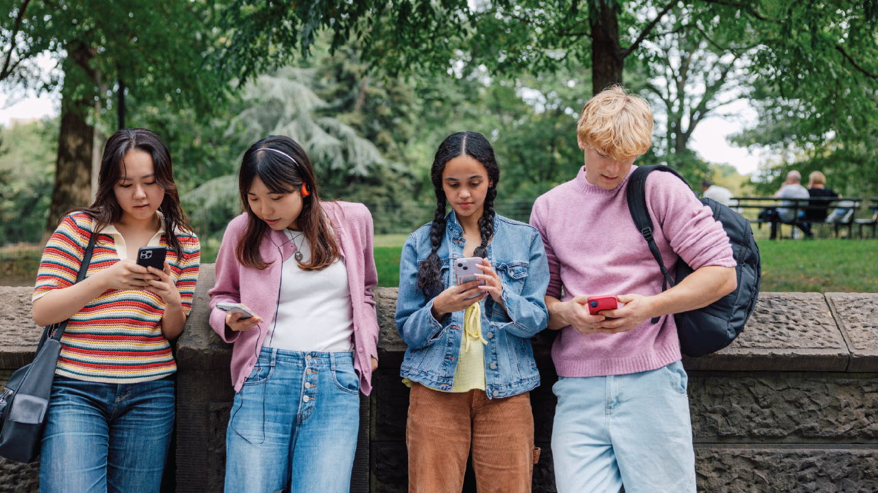 An image of four teenagers looking at their cellphones