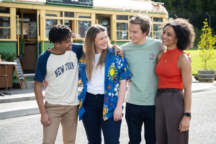 Dex, Cara, JJ and Remi look at one another outside of the 82 tram in Neighbours