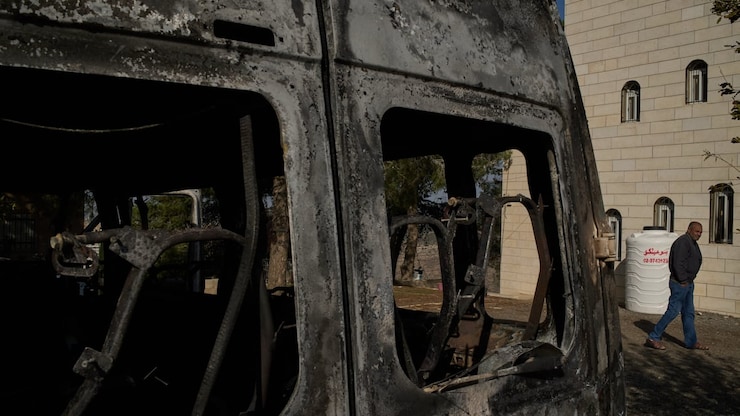 A man walks past a vehicle burned during an attack by Israeli settlers in the West Bank village of al-Jab'a, near Bethlehem, on Nov. 18. 