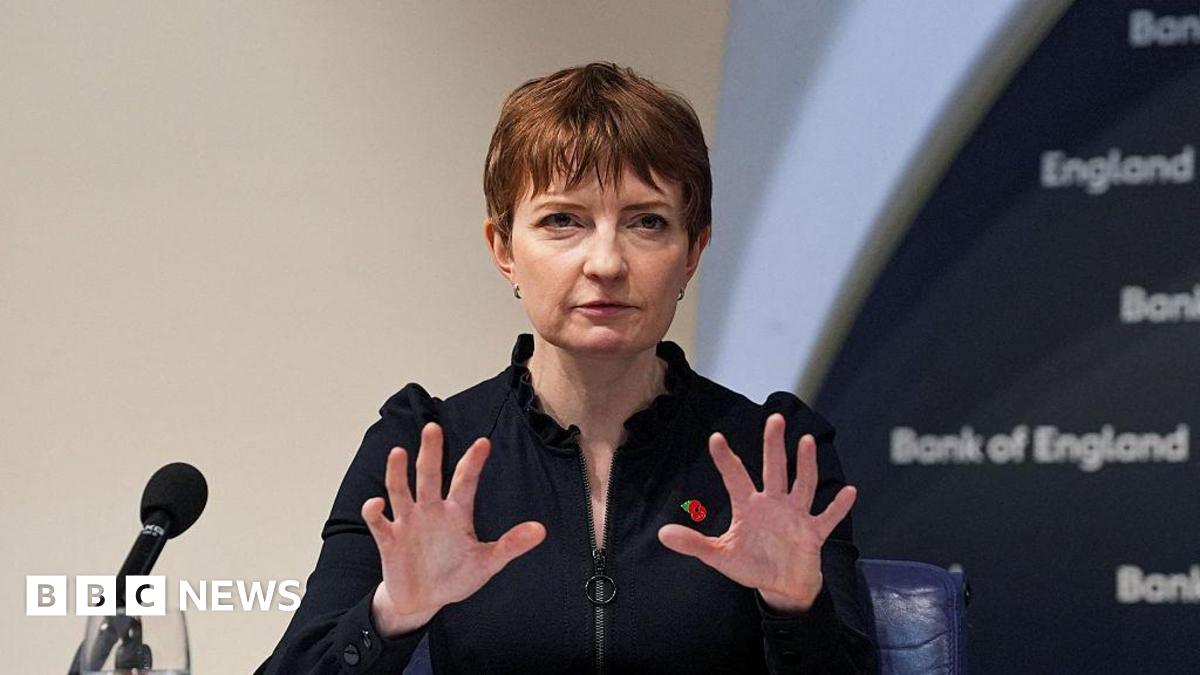 A brown NC500 sign post which says it is 27 miles to Ullapool next to a country road with hills in the background.