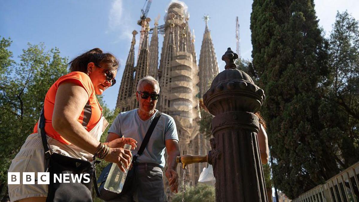 People refill their bottles at a public fountain in front of the Sagrada Familia basilica in Barcelona