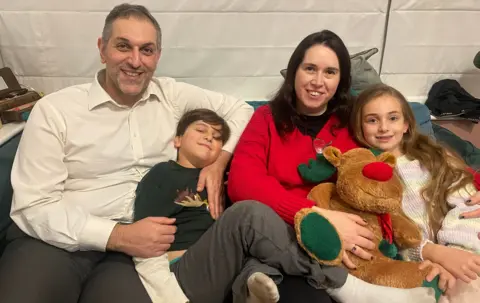 Omid, Deborah and their children on the sofa with a Rudolph cuddly toy