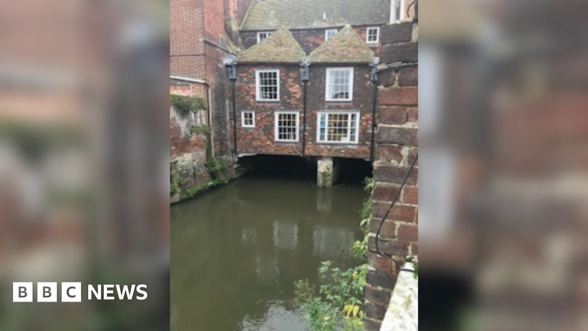 A Medieval building with arched windows and a low entrance, made from black bricks.