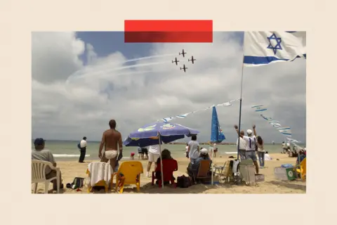 AFP via Getty Images People gather on the beach in the Mediterranean city of Tel Aviv to watch a military show marking Israeli Independence Day