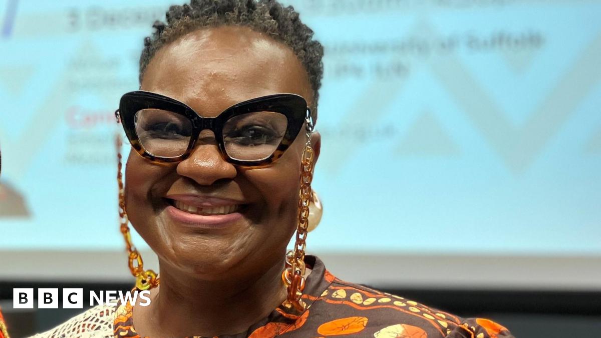 Valerie wearing glasses, with short dark hair, beams at the camera