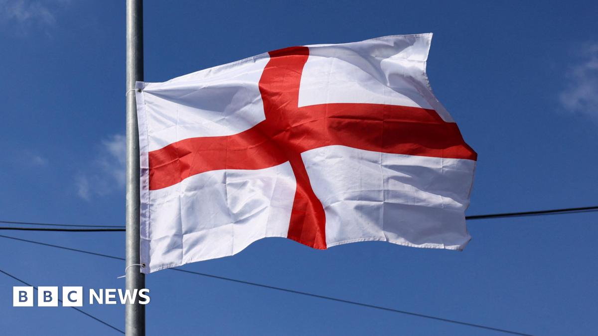 An England flag with the cross of St George on it flaps in the breeze after being attached to a lamp-post.