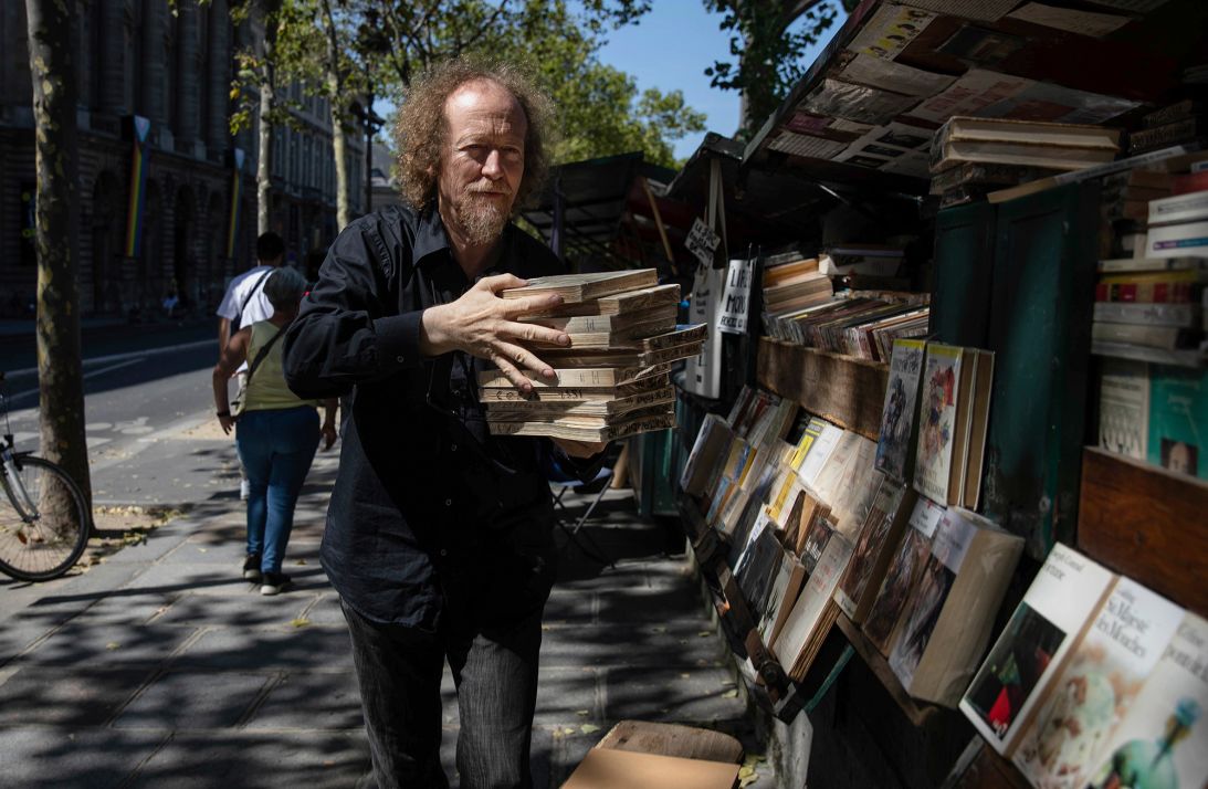 Jérôme Callais, head of the Paris Booksellers' Cultural Association, carries books at his booth along the Seine riverbank in 2023.