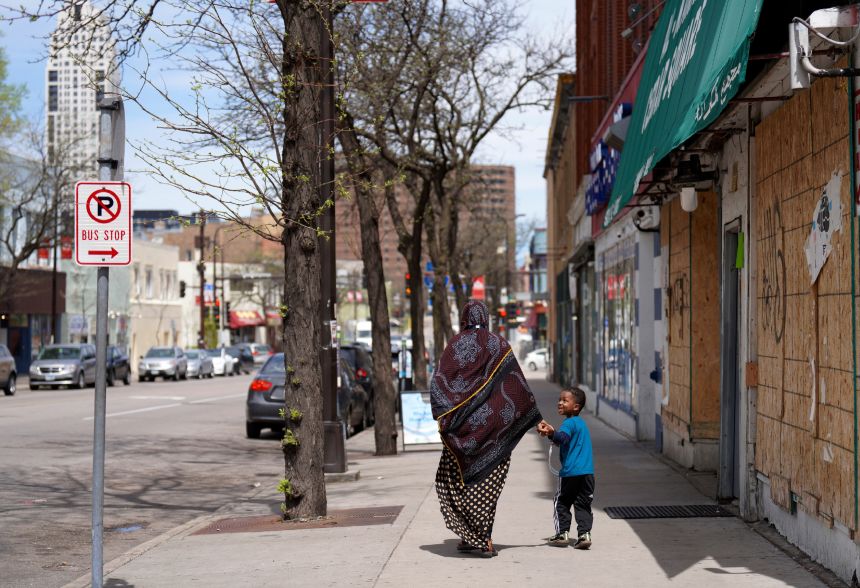 A woman and a child hold hands as they walk down a street in the predominantly Somali neighborhood of Cedar-Riverside in Minneapolis, on May 12, 2022.
