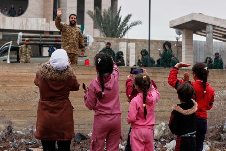 Syrian children take pictures of soldiers before a parade by the new Syrian army, part of celebrations marking the first anniversary of the ousting of the Bashar al-Assad regime in Douma, on the outskirts of Damascus, Syria, on Monday.