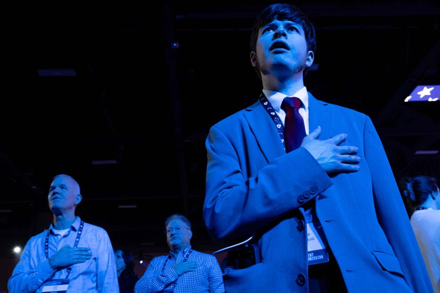 Attendees stand and observe the National Anthem during Turning Point USA's AmericaFest 2025 in Phoenix on December 19, 2025.