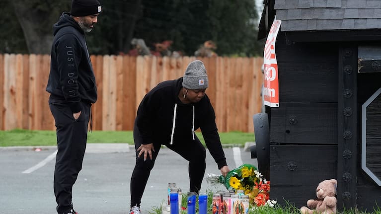 Aundre Smith, left, watches as Genesis Smith places flowers near the scene of a mass shooting on Saturday at a banquet hall in Stockton.