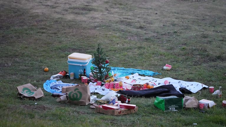 A small Christmas tree is at the center of an abandoned holiday picnic at Bondi Beach after a reported shooting in Sydney