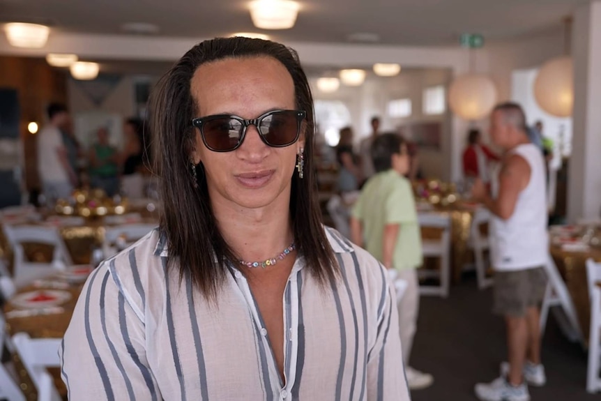 Sebastian Cassie orgnaiser of bondi beach lunch for the community wears sunnies indoors as he speaks to the medai