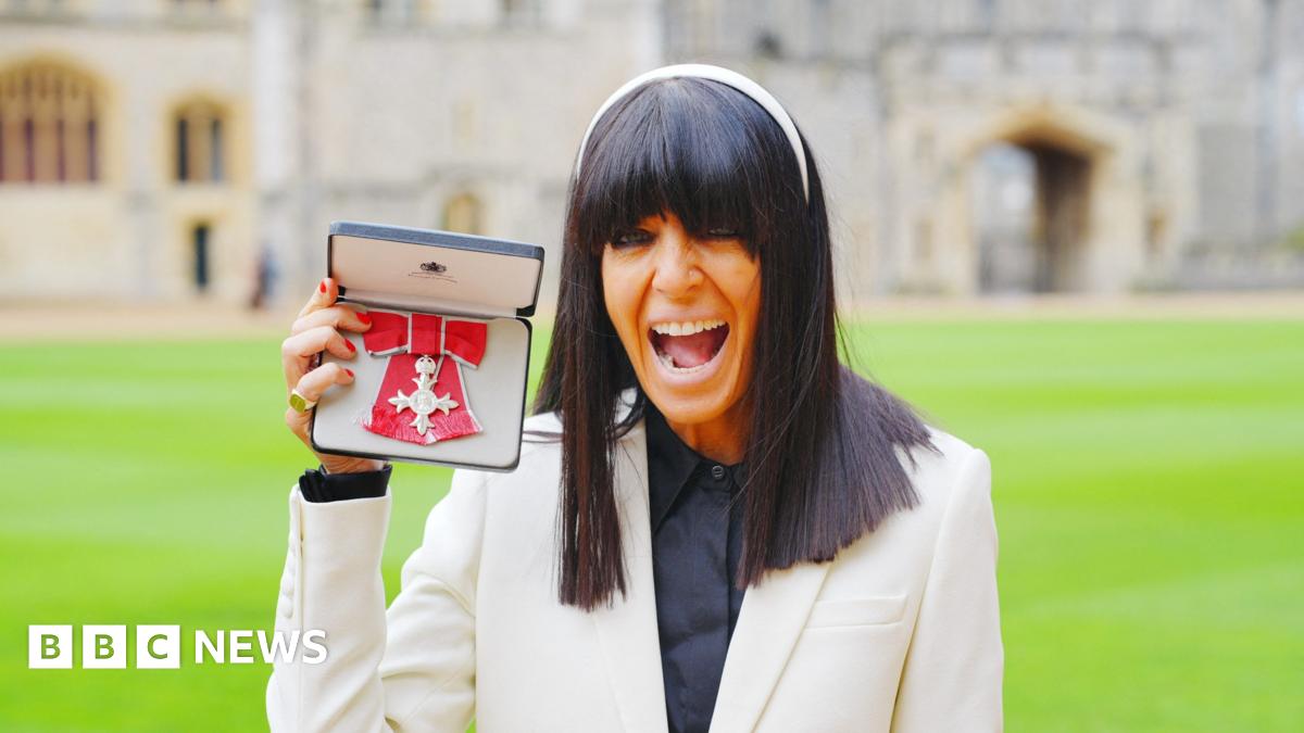 Claudia Winkleman shaking hands with King Charles III while being made an MBE at a ceremony at Windsor Castle