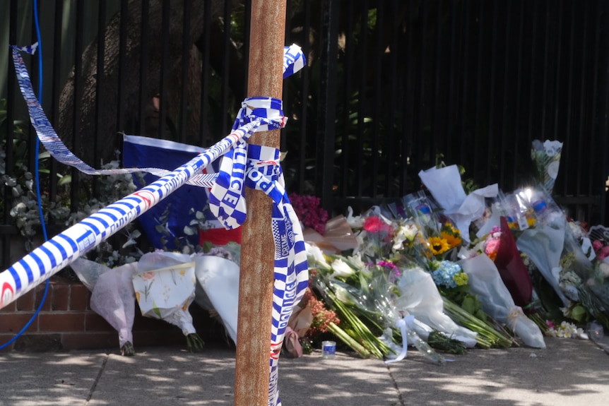 Flowers on ground behind police tape