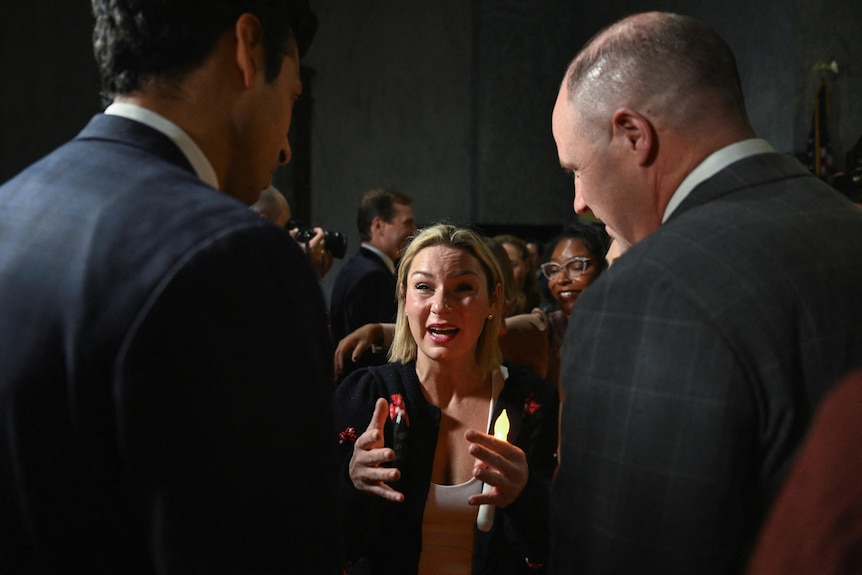 A woman sobs as she speaks to two men