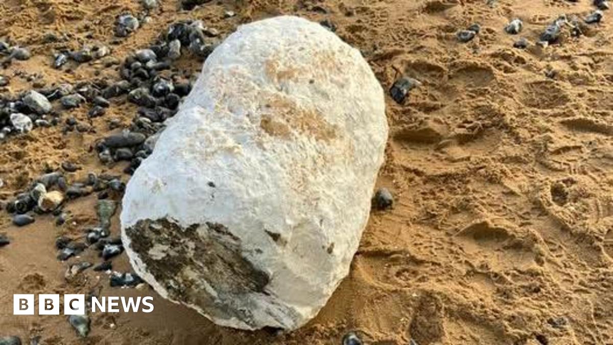 A large white barrel-shaped object on a beach.