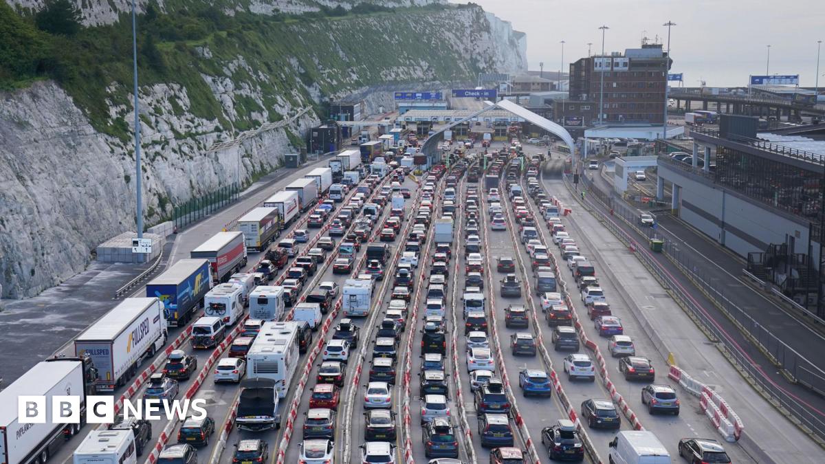 An aerial view over vehicles queuing at the Port of Dover. There are white cliffs on the left and the ocean on the right.
