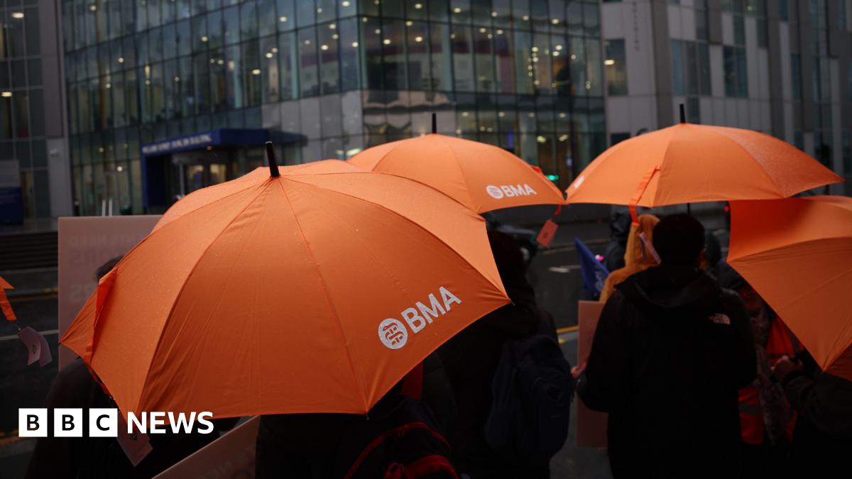 A number of orange umbrellas with the logo 'BMA' on the side, standing in front of a hospital