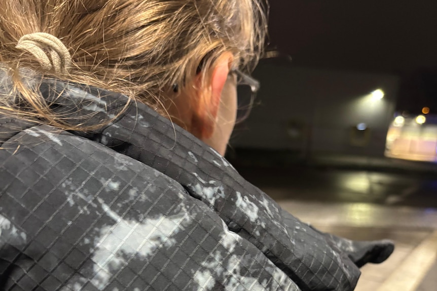 A man in a cloudy jacket is pictured looking out at a street,.