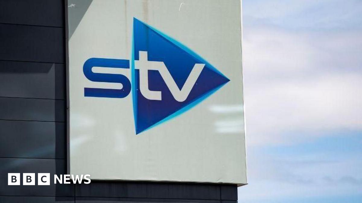 Close up of a blue and white STV sign on a building, photographed against a cloudy blue sky