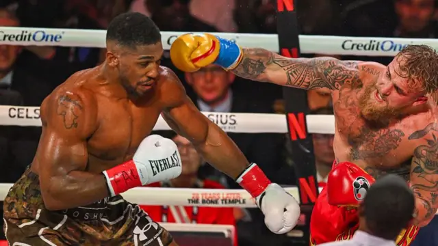 Joshua in the ring with Jake Paul with his Nigeria tattoo visible on his right shoulder