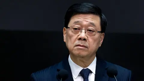 Getty Images John Lee, Hong Kong's chief executive, standing at the podium during a news conference on the fire