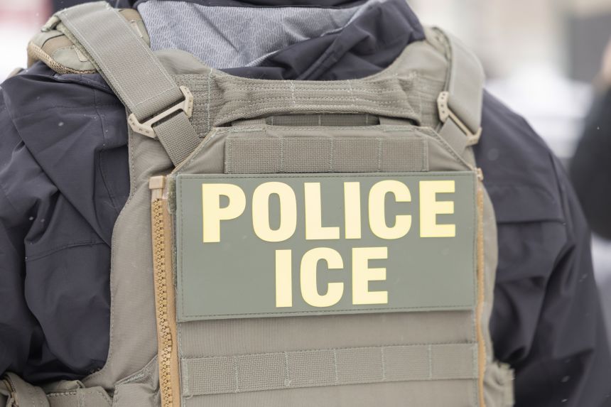 Immigration and Customs Enforcement officers question a man's status on Lake Street near a Somali mall called the Karmel Mall in Minneapolis on Wednesday.