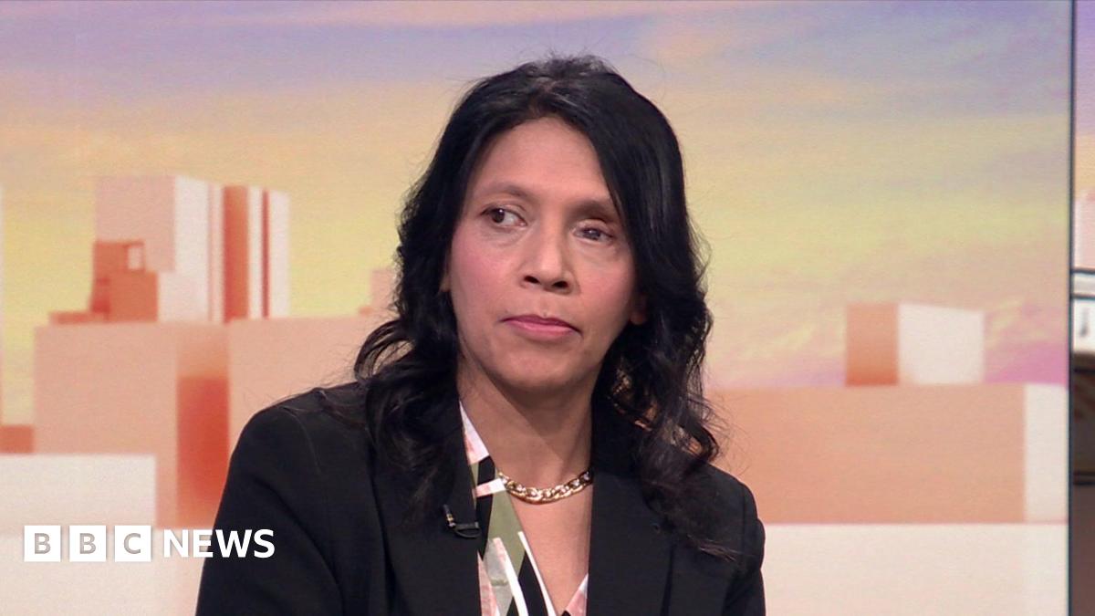 Dr Halima Begum sitting down wearing a black jacket and colourful top. She has dark, shoulder-length hair.