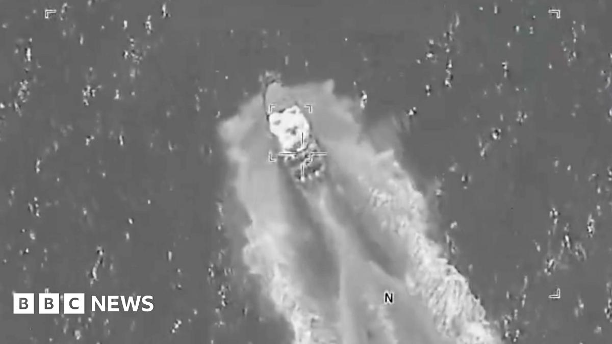 A greyscale aerial image shows a small boat speeding through a stretch of water, with a small square of focus visible in the centre.