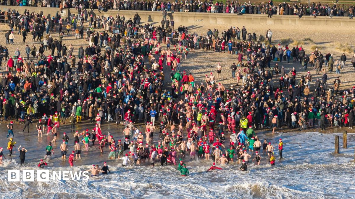 Swimmers enter the North Sea in Lowestoft, watched by crowds of people