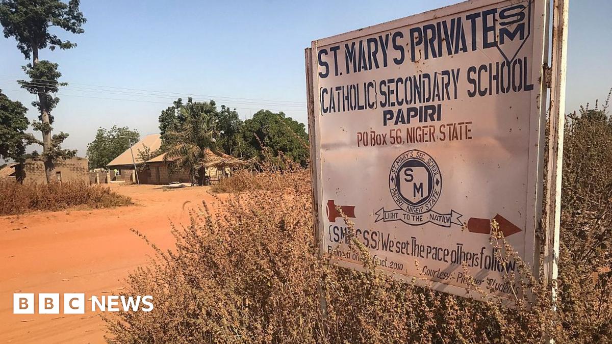 A sign that reads St. Mary's Private Catholic Secondary School Papiri, Niger State, is positioned on the right with red dirt road and a building in the background surrounded by trees.
