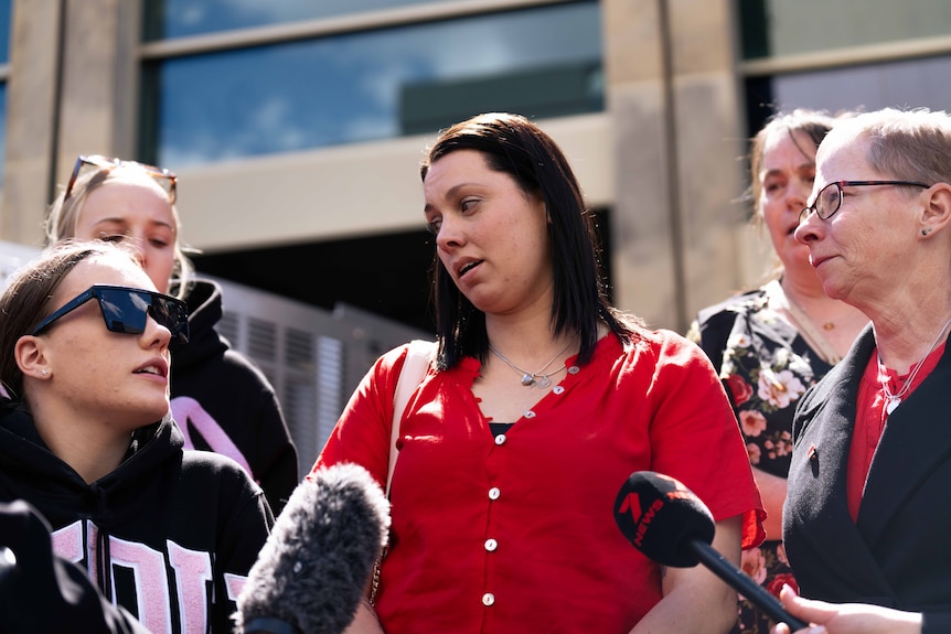 A group of people speak to media outside court