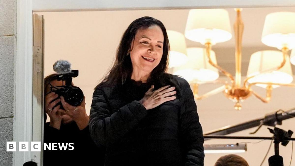 Maria Corina Machado jumps over barricades outside the Grand Hotel in Oslo to greet cheering supporters as security looks on.