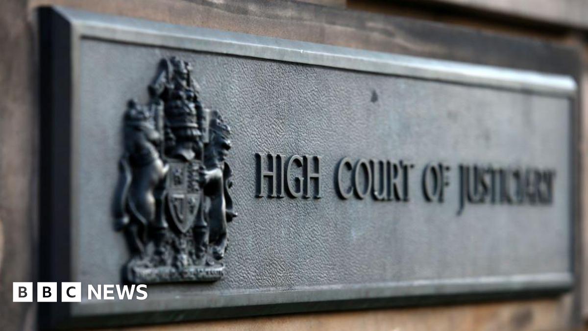 A metal sign reading High Court of Justiciary attached to a wall outside the High Court in Edinburgh