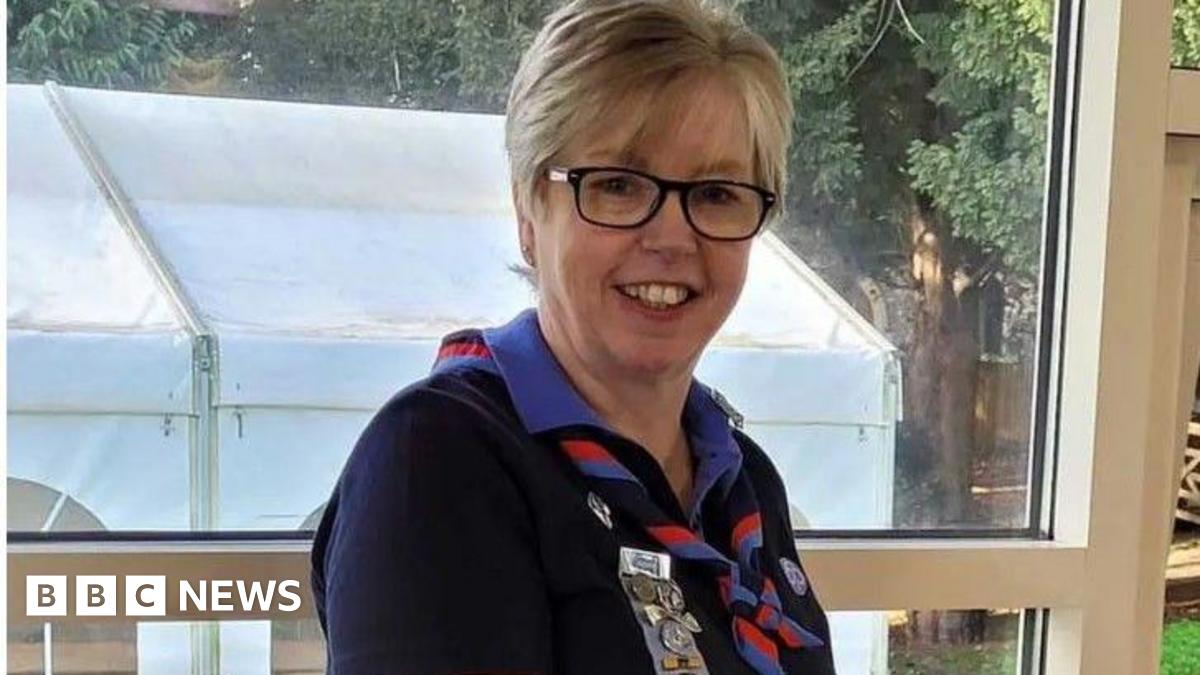Tracy Foster wears a girl guides' uniform of cornflower blue shirt with a navy jumper and a twisted knotted red and cornflower blue scarf round her jumper.