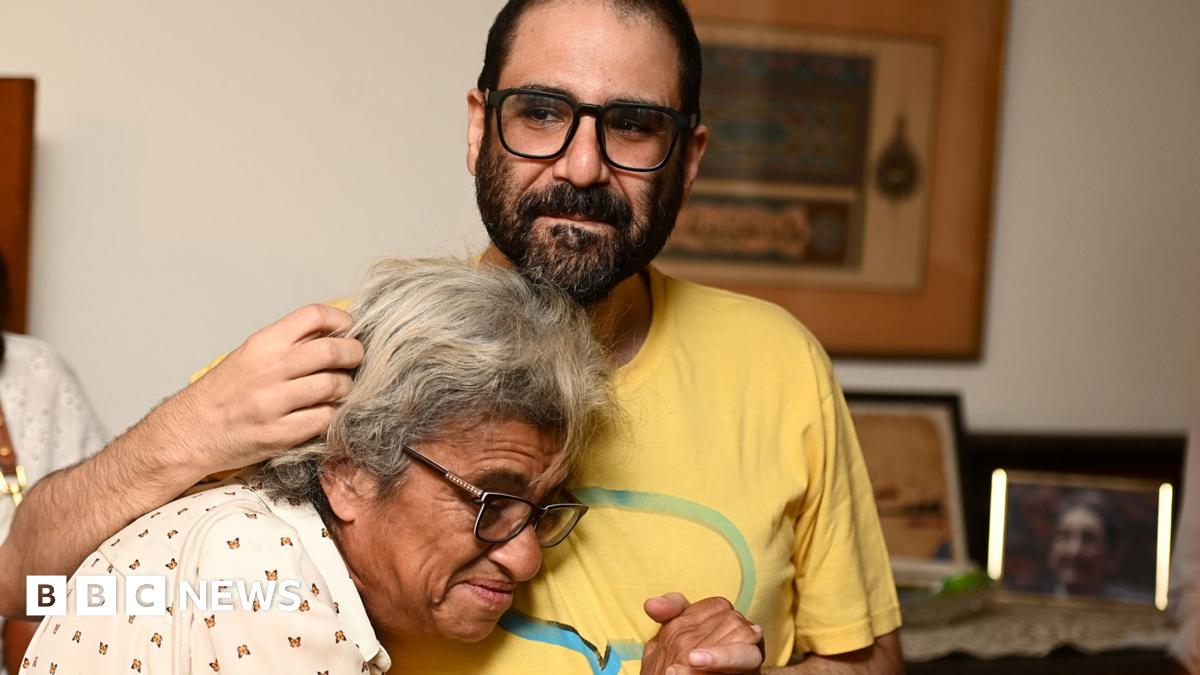Alaa Abd El Fattah pictured hugging his mother after being released as a hostage wearing a yellow t-shirt