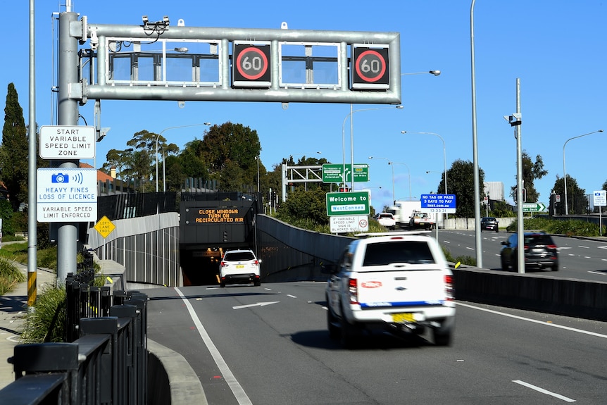 Cars driving  towards the entrance of a tunnel.
