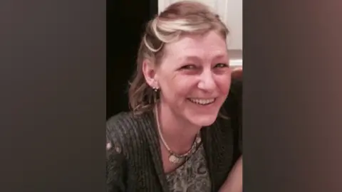 Handout Dawn Sturgess in a grey cardigan, smiling to the camera. She has brown hair with blonde streaks. 