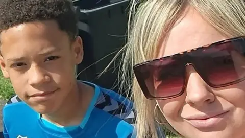 Carley James Carley with blonde hair and wearing sunglasses is pictured with her son who is wearing a blue football kit