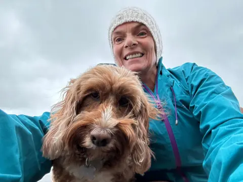 Mary-Jane Parker Mary-Jane in a white woolly hat and blue jacket with her dog
