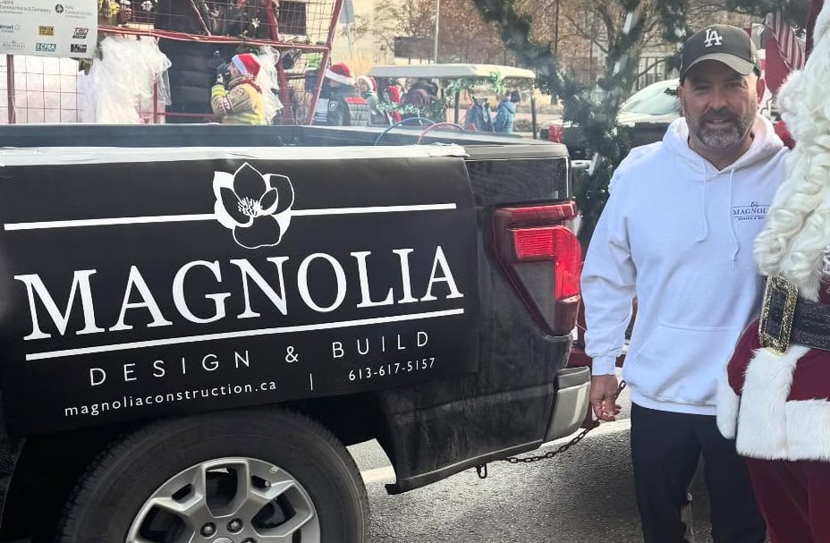 A man stands in front of a truck with a logo that reads 'Magnolia Design & Build.'