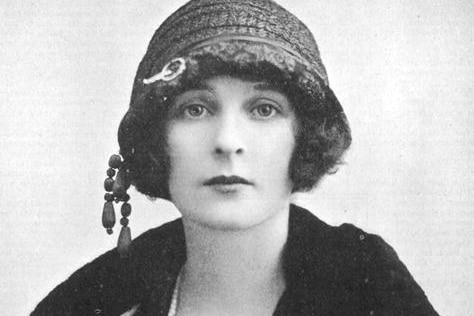 Freda wears a flapper-style hat and looks at camera without smiling