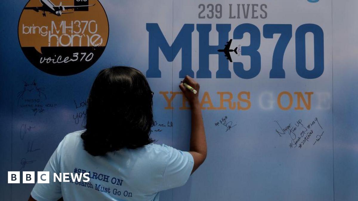 A family member writes on a message board for passengers onboard the missing Malaysia Airlines Flight MH370 at an event in Kuala Lumpur. "The Search Must Go On," her t-shirt reads.