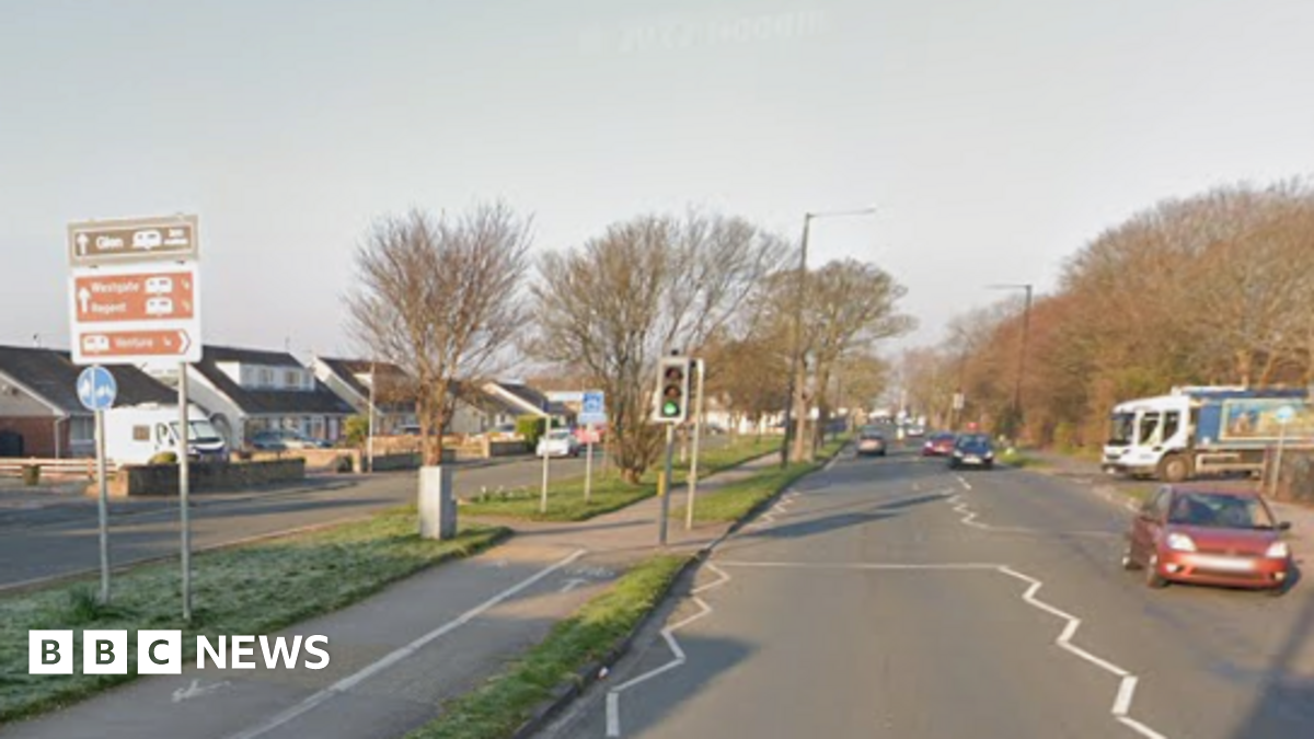 A red car drives alongside Westgate in Morecambe, with a lorry behind about to turn into the road
