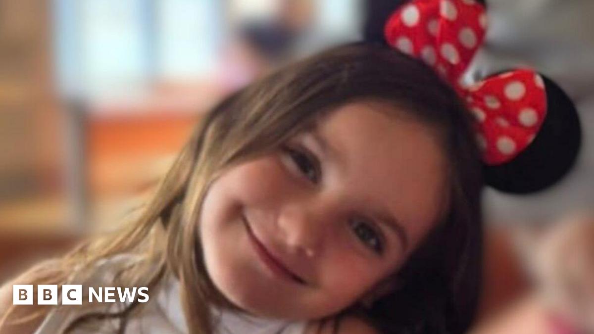 A close-up picture of Aria Thorpe. She is leaning her head to the side and she is smiling. On top of her head are Minnie Mouse ears.