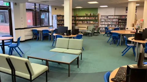 An empty classroom during the two day closure last week. There is a number of chairs that are empty surrounding by books and computers. There is also a number of tables and a couple of computers.