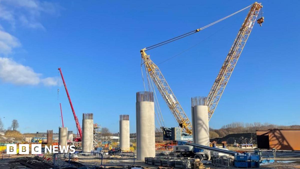 A large building site with a yellow crane towering above pillars that will form the base of a viaduct.