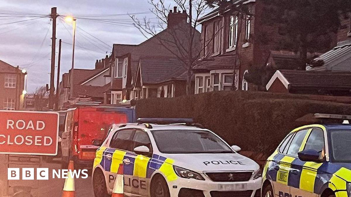 Two police vehicles parked in a cordon on Salisbury Avenue, Blackpool, next to a red and white 'road closed' sign.